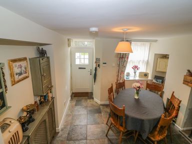A dining area with a round table covered with a dark cloth and wooden chairs near a door at Shandrum Brook in Charleville
