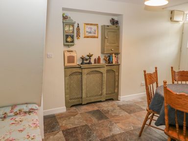 A dining area with a table covered by a dark cloth and wooden chairs next to a built-in cabinet with various decorative items at Shandrum Brook in Charleville
