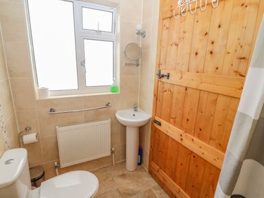 A bathroom with a toilet sink wooden door and window at Shandrum Brook in Charleville