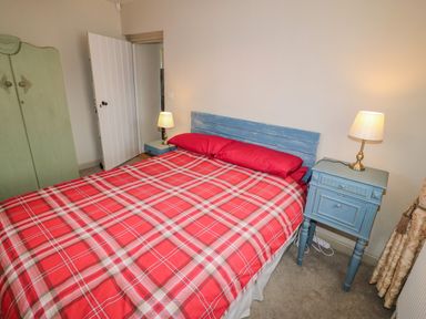 A bedroom with a red plaid bedspread and two blue nightstands with lamps at Shandrum Brook in Charleville