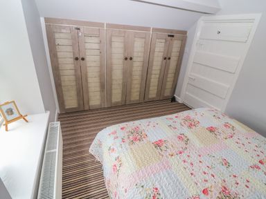 A bedroom with striped carpet floral quilted bedspread wooden closets and a white door at Shandrum Brook in Charleville