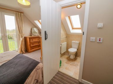 A bedroom with bed dresser and an open door leading to a bathroom with a toilet and skylight at Shandrum Brook in Charleville