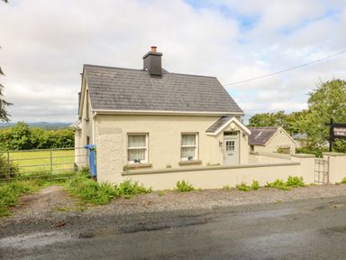 A cream-colored house with a grey roof behind a low wall and a gated driveway at Shandrum Brook in Charleville