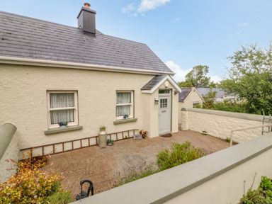 The exterior of a cream colored house with two windows and a door in a fenced yard at Shandrum Brook in Charleville