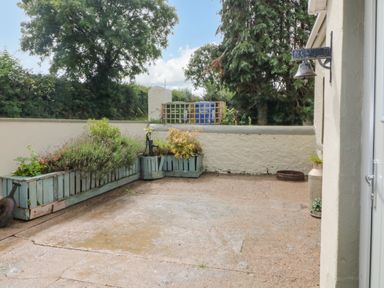 An outdoor patio area with potted plants and a bell on the wall at Shandrum Brook in Charleville