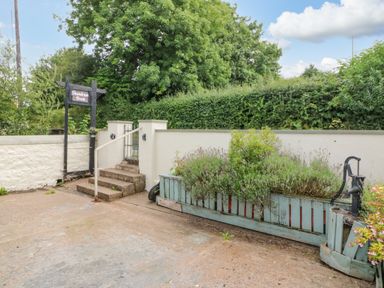 An outdoor area with concrete steps leading to a gate and a planter box with greenery at Shandrum Brook in Charleville