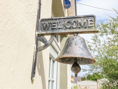 A metal welcome sign with a bell mounted on an exterior wall near a window at Shandrum Brook in Charleville