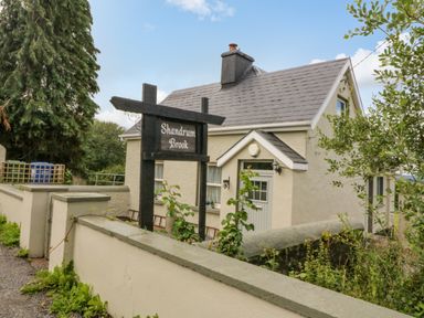 A house with a sign reading Shandrum Brook outside and a garden wall surrounding the property at Shandrum Brook in Charleville