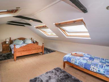 A bedroom with two beds wooden furniture skylights on a slanted ceiling at Taliharris Cottage in Llandysul