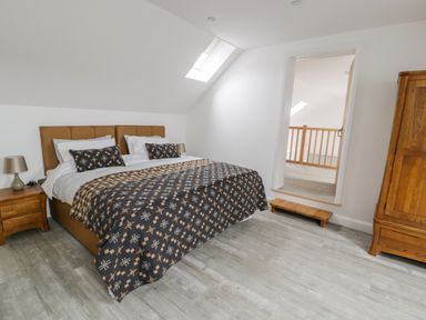A bedroom with a double bed bedside tables lamps and a wooden wardrobe at Sgubor in Pentraeth
