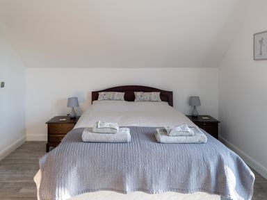 A bedroom with a double bed two bedside tables and lamps at Sgubor in Pentraeth