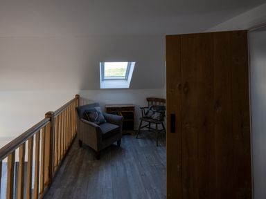 A small seating area with two chairs and a side table under a skylight window at Sgubor in Pentraeth