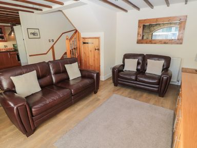 A living room with two brown leather sofas a wooden staircase and a wall mirror at The Mistal in Glanton near Alnwick