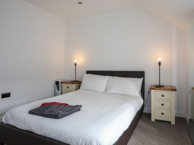 A bedroom with a bed with white bedding two bedside tables with lamps and folded towels on the bed at The Old Post Office 23 High Street in Cemaes Bay