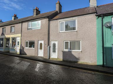 A row of terraced houses on a street with a clothing sales shop at The Old Post Office 23 High Street in Cemaes Bay