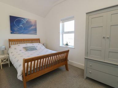 A bedroom with a bed and wardrobe at Little Orme View in Llandudno
