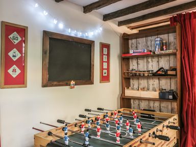 A game room with a foosball table shelves with board games and a blackboard at Beulah Cottage in Green Bottom near Littledean