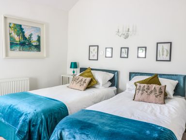 A bedroom with two single beds with blue throws and decorative pillows at Beulah Cottage in Green Bottom near Littledean