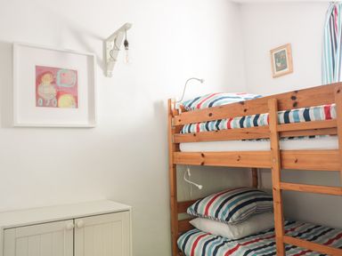 A bedroom with a wooden bunk bed with striped bedding a small cabinet and framed pictures on the wall at Beulah Cottage in Green Bottom near Littledean