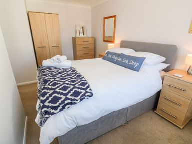 A bedroom with a bed with pillows and blanket two bedside tables a chest of drawers and a wardrobe at Rockpool in Harlyn Bay near St Merryn