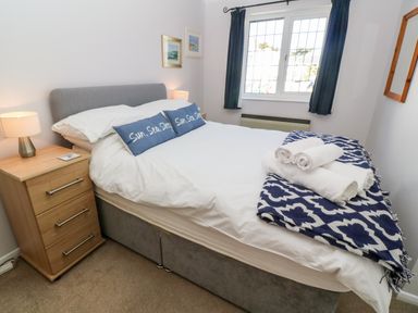 A bedroom with a double bed bedside table lamps and a window with dark curtains at Rockpool in Harlyn Bay near St Merryn