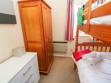 A bedroom with a wooden bunk bed a wooden wardrobe and a white chest of drawers at Rockpool in Harlyn Bay near St Merryn