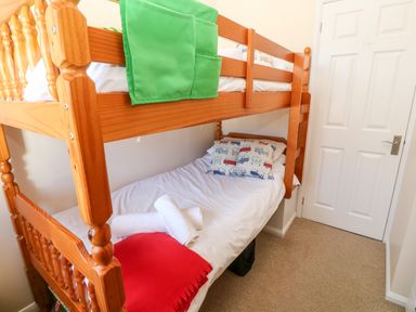 A small bedroom with a wooden bunk bed and white bedding at Rockpool in Harlyn Bay near St Merryn