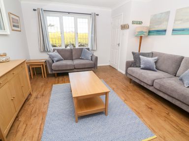 A living room with two gray sofas a wooden coffee table a patterned rug and a sideboard at Rockpool in Harlyn Bay near St Merryn