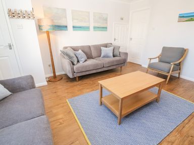 A living room with two sofas cushioned chair wooden coffee table and a floor lamp at Rockpool in Harlyn Bay near St Merryn