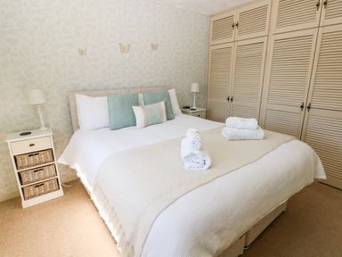 A bedroom with a bed with pillows and folded towels and built in cupboards at The Elms in Milford Haven