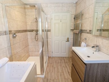 A bathroom with a shower cubicle sink cabinet heated towel rail and a bathtub at The Elms in Milford Haven