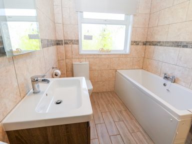 A bathroom with a sink, toilet, bathtub, and window at The Elms in Milford Haven