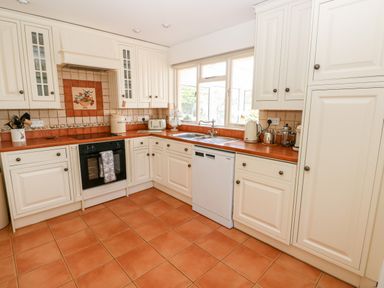 A kitchen with white cabinets and orange countertops near a window at The Elms in Milford Haven