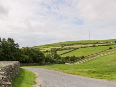 A landscape with a winding road, hills, and a telecommunications tower at Elm Lodge in Ulverston