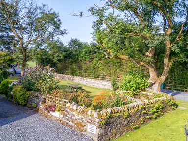 A garden with a picnic table and flower beds at Elm Lodge in Ulverston