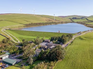 An aerial view of a lake surrounded by fields and farm buildings at Elm Lodge in Ulverston