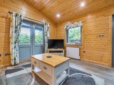 A living room with a television and a coffee table at Elm Lodge in Ulverston