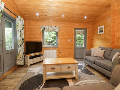 A living room with a sofa, coffee table, and television at Elm Lodge in Ulverston