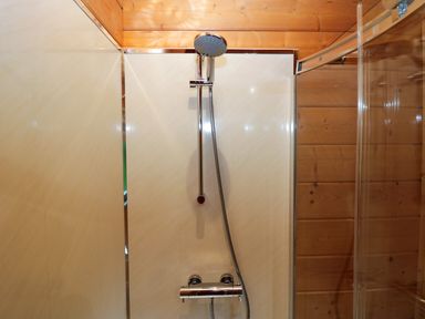 A shower with a wall and faucet at Elm Lodge in Ulverston