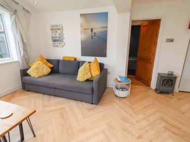 A living room with a sofa and wall art at Sunrise Cottage in Beadnell