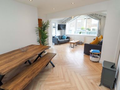 A living room with a dining table and benches at Sunrise Cottage in Beadnell