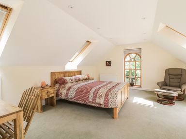 A bedroom with a bed table chair and armchair near windows at Squirrels Drey in Little Dunham near Litcham