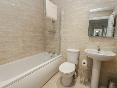 A bathroom with a bathtub shower toilet sink and mirror at Manor Heath Apartment 1 in Scarborough