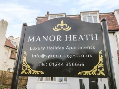 A black signboard with gold decorations displaying information about Manor Heath luxury holiday apartments in Scarborough