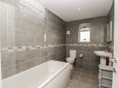 A bathroom with a bathtub toilet sink and window at Manor Heath Apartment 4 Scarborough