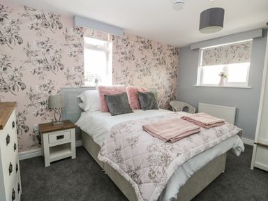 A bedroom with a double bed and floral wallpaper at Manor Heath Apartment 4 in Scarborough