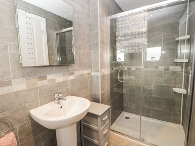 A bathroom with a pedestal sink mirror and glass-enclosed shower at Manor Heath Apartment 4 in Scarborough