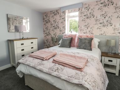 A bedroom with a bed with pillows and folded towels a bedside table with a lamp a chest of drawers with a mirror on the wall at Manor Heath Apartment 4 in Scarborough