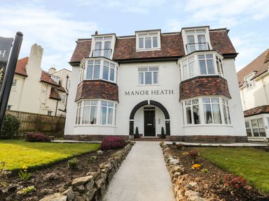 A pathway leading to the entrance of a three-story house with bay windows and a tiled roof at Manor Heath Apartment 4 in Scarborough