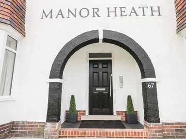 The entrance of Manor Heath Apartment 4 with a black door under a black arch and two small potted plants in Scarborough